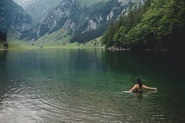 woman swimming in a lake surrounded by mountains