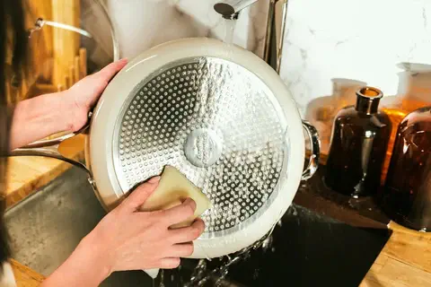 Rinsing a ceramic pan and demonstrating how to clean a ceramic pan