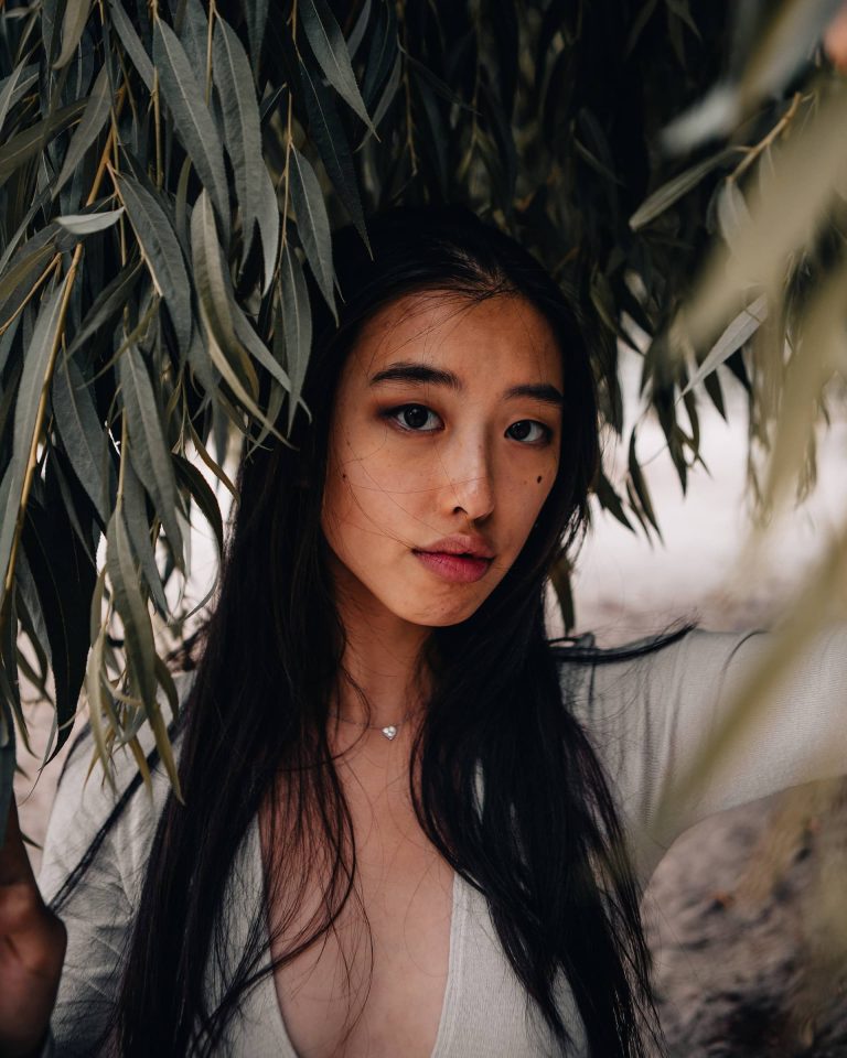 Woman in front of trees with long dark hair